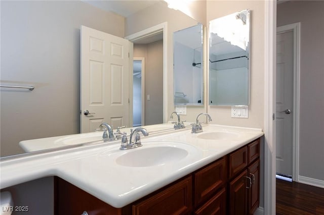 bathroom featuring double vanity, wood finished floors, and a sink