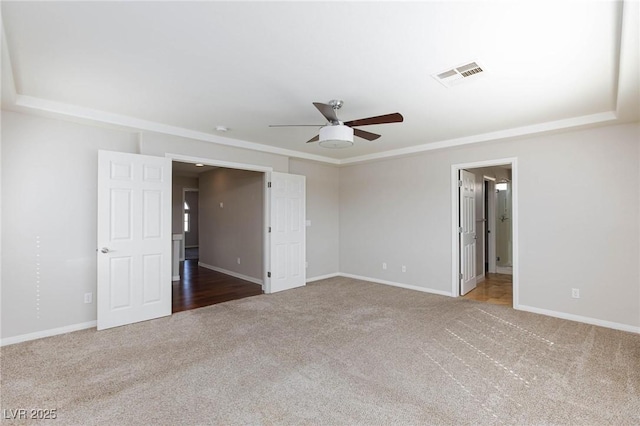 spare room with a ceiling fan, visible vents, carpet floors, and baseboards