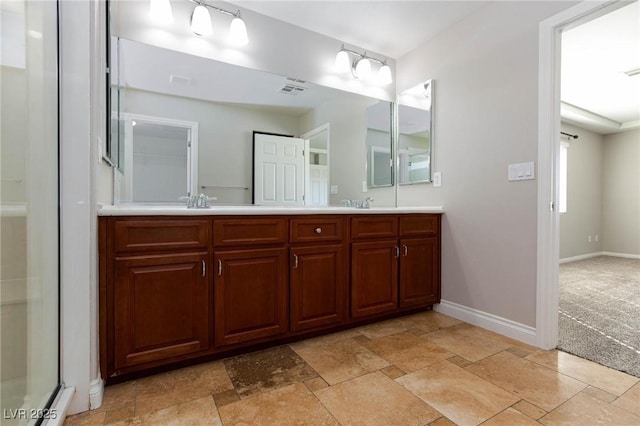 full bathroom with a sink, double vanity, baseboards, and stone finish flooring