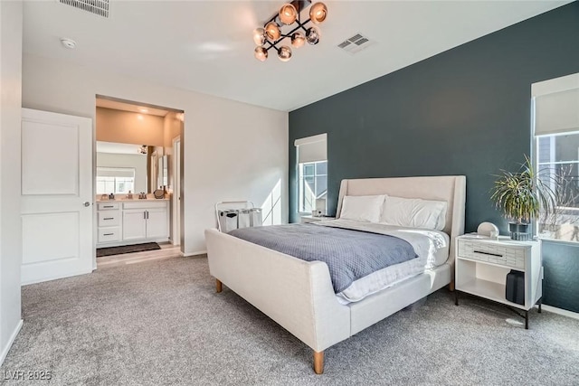 bedroom with visible vents, ensuite bathroom, baseboards, and carpet flooring