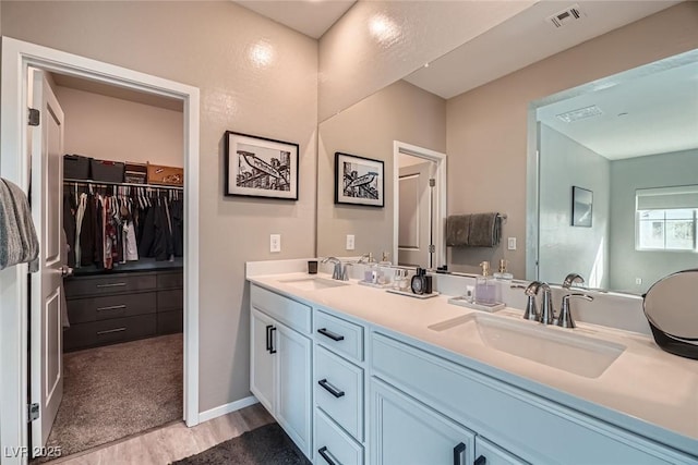 bathroom with a sink, visible vents, a spacious closet, and double vanity