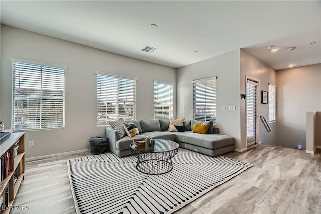 living area with visible vents, a healthy amount of sunlight, baseboards, and light wood-style floors