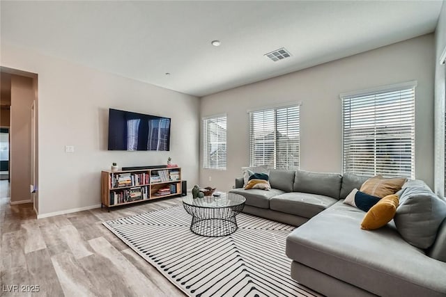 living room with light wood-style flooring, baseboards, and visible vents