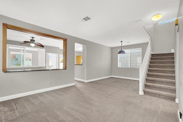 unfurnished living room featuring visible vents, ceiling fan, baseboards, stairway, and carpet floors