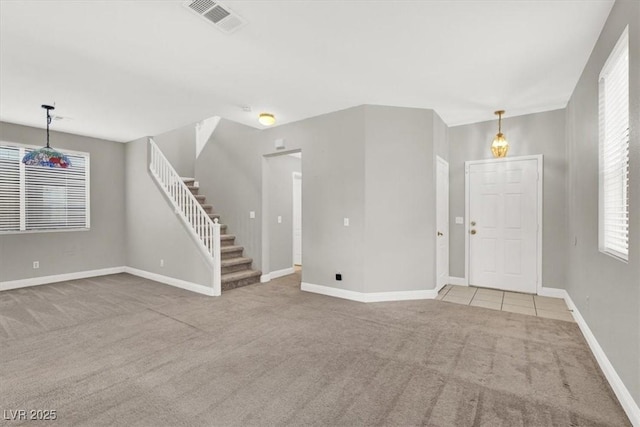 unfurnished living room featuring stairs, carpet flooring, baseboards, and visible vents