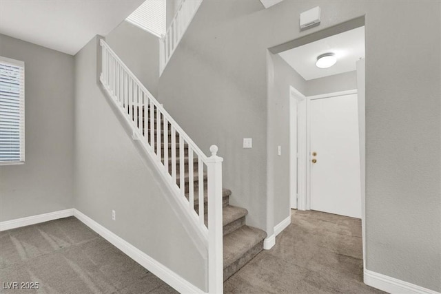 stairway featuring baseboards and carpet floors