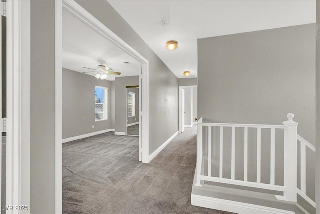 hall featuring carpet flooring and baseboards