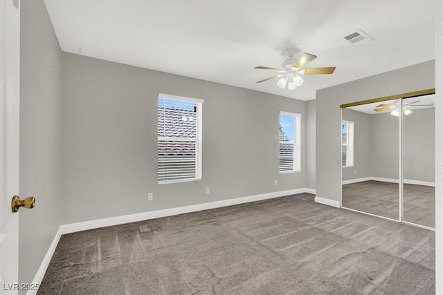 unfurnished bedroom featuring visible vents, multiple windows, baseboards, and carpet flooring