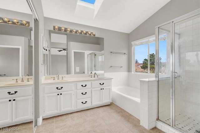 full bath featuring a bath, a shower stall, vaulted ceiling with skylight, and a sink