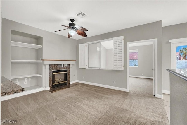 unfurnished living room featuring visible vents, carpet flooring, a healthy amount of sunlight, and ceiling fan