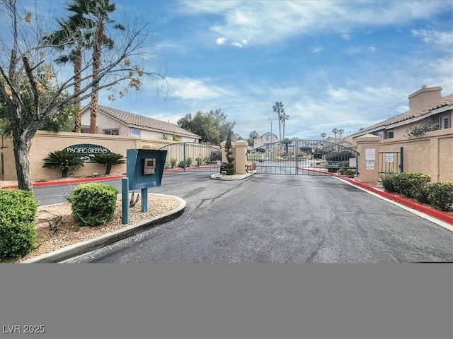 view of road featuring a gate, curbs, and a gated entry