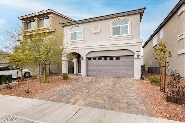 mediterranean / spanish house with stucco siding, decorative driveway, and an attached garage