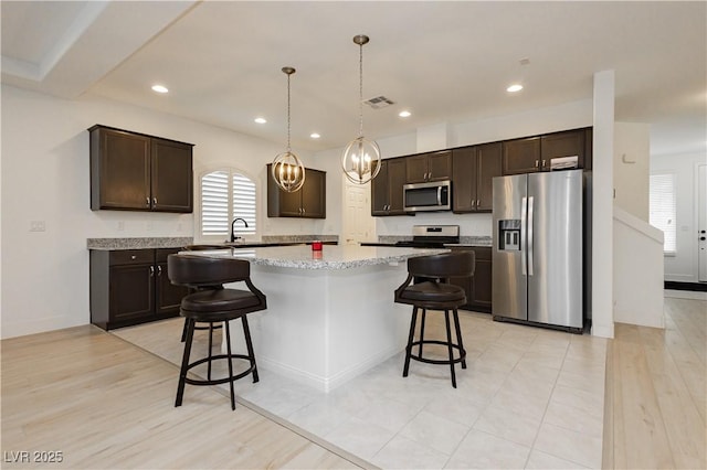 kitchen with visible vents, a kitchen breakfast bar, dark brown cabinetry, and appliances with stainless steel finishes