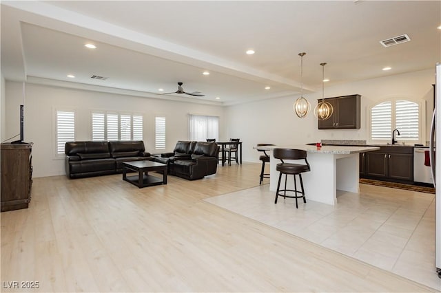 living area with visible vents, beam ceiling, recessed lighting, ceiling fan, and light wood-style floors