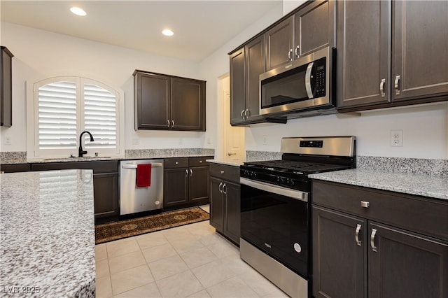 kitchen featuring a sink, light stone counters, recessed lighting, appliances with stainless steel finishes, and dark brown cabinets