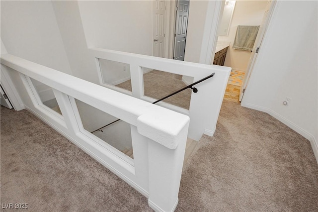 staircase featuring baseboards and carpet