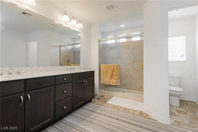 full bathroom with visible vents, toilet, a sink, a shower stall, and double vanity