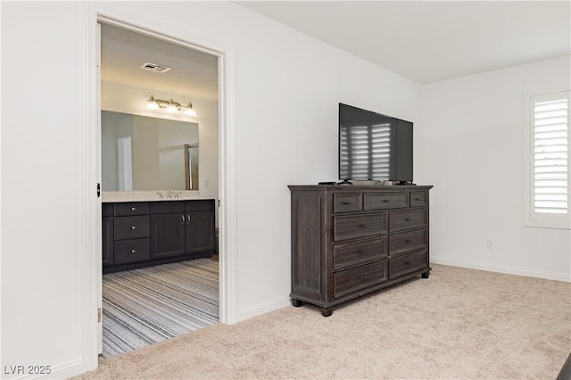 bedroom featuring visible vents, a sink, connected bathroom, baseboards, and light colored carpet