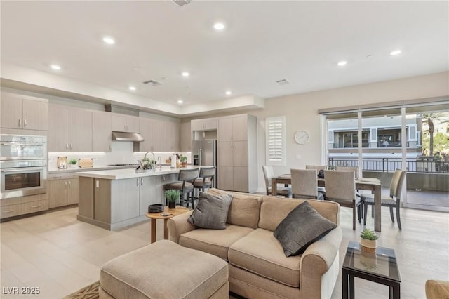 living area featuring recessed lighting, visible vents, and light wood finished floors