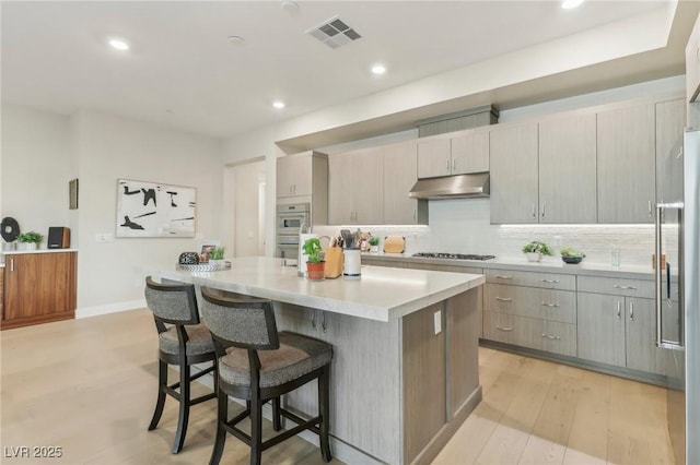 kitchen with visible vents, a kitchen island, gas stovetop, high end fridge, and under cabinet range hood