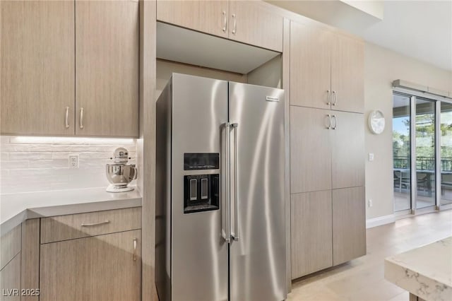 kitchen featuring tasteful backsplash, light brown cabinets, baseboards, light countertops, and high end fridge