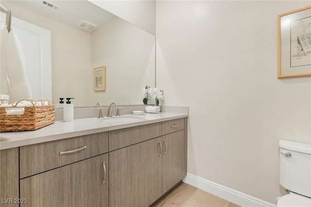 bathroom with visible vents, baseboards, toilet, and vanity