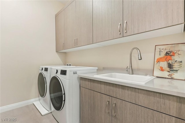 clothes washing area with light tile patterned floors, baseboards, cabinet space, a sink, and washer and clothes dryer