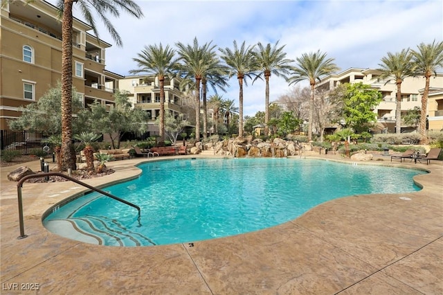 community pool with a patio and fence