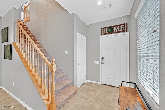 foyer entrance with visible vents, plenty of natural light, stairway, and baseboards