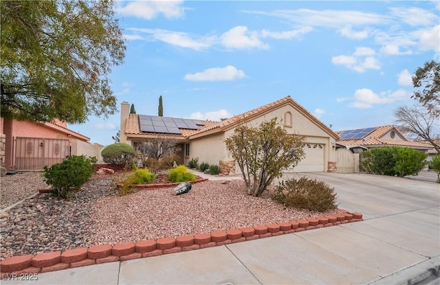 view of front of house with driveway, stucco siding, a garage, a tile roof, and roof mounted solar panels