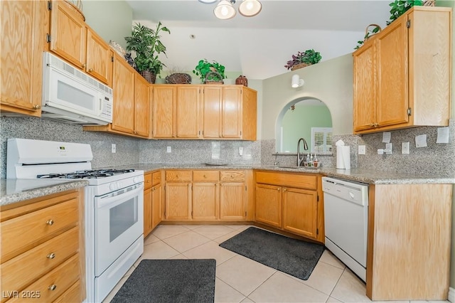 kitchen featuring white appliances, light stone counters, light tile patterned flooring, a sink, and backsplash