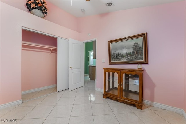 unfurnished bedroom featuring light tile patterned floors, baseboards, visible vents, and a closet