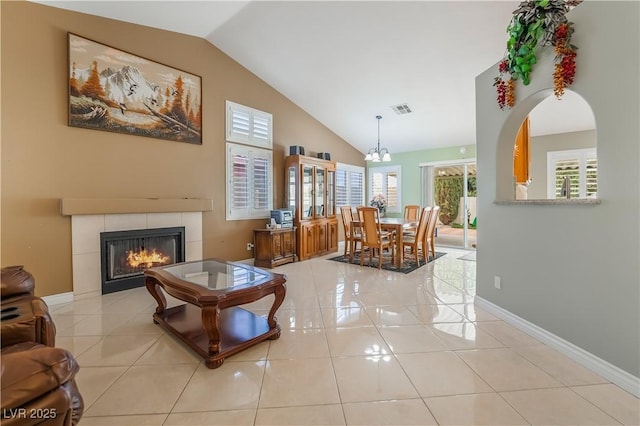 tiled living room featuring baseboards, visible vents, high vaulted ceiling, an inviting chandelier, and a tile fireplace