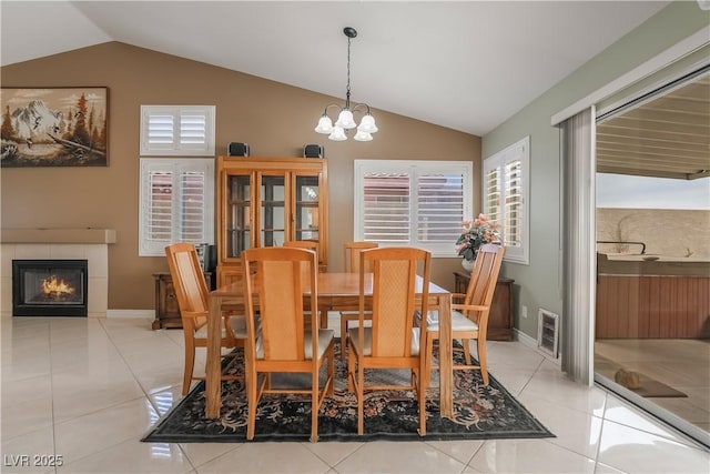 dining space featuring plenty of natural light, an inviting chandelier, a tiled fireplace, and tile patterned flooring