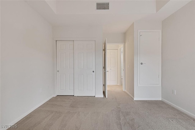 unfurnished bedroom with baseboards, carpet floors, a closet, and visible vents