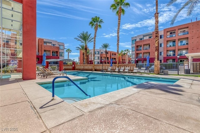 pool with a patio area and fence