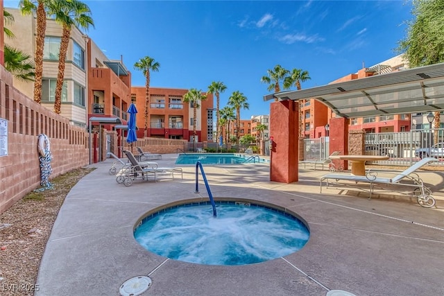 community pool with a patio, a community hot tub, and fence