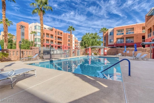 community pool with a patio area and fence