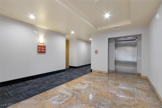 empty room with visible vents, baseboards, elevator, recessed lighting, and a raised ceiling