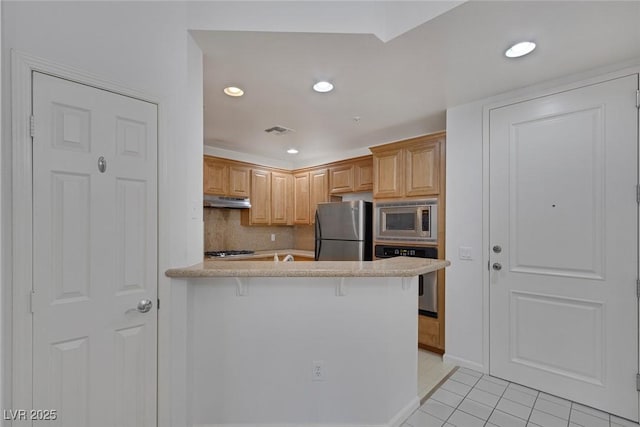 kitchen featuring visible vents, a peninsula, decorative backsplash, under cabinet range hood, and appliances with stainless steel finishes