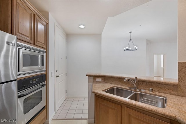 kitchen featuring light stone counters, light tile patterned floors, a notable chandelier, stainless steel appliances, and a sink