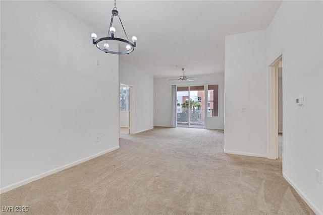 empty room featuring light carpet, ceiling fan with notable chandelier, and baseboards