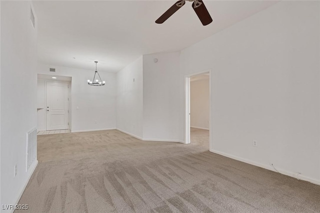 empty room with ceiling fan with notable chandelier, visible vents, and light carpet