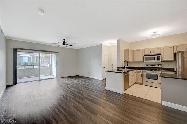 kitchen featuring a peninsula, ceiling fan, a sink, appliances with stainless steel finishes, and dark countertops