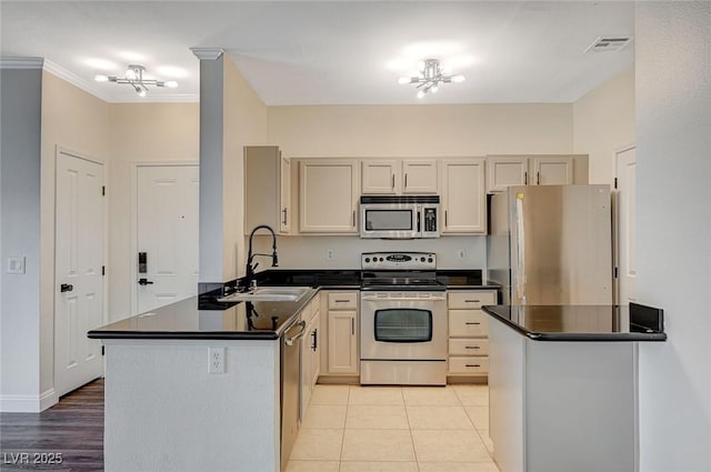 kitchen featuring visible vents, a notable chandelier, a sink, dark countertops, and stainless steel appliances