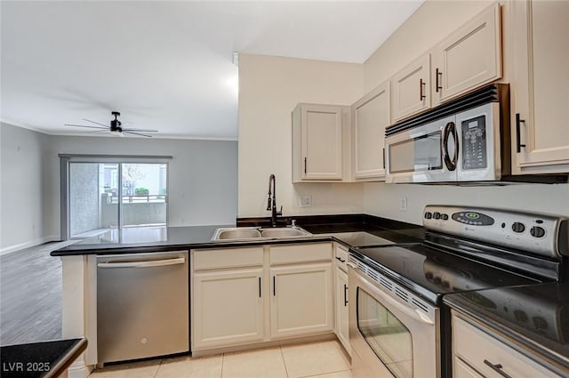 kitchen featuring a peninsula, a sink, ceiling fan, stainless steel appliances, and dark countertops