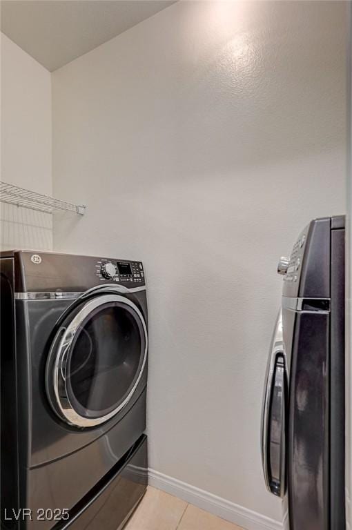 laundry room featuring baseboards, washing machine and dryer, light tile patterned flooring, and laundry area