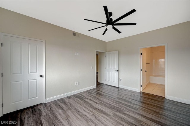 unfurnished bedroom featuring visible vents, ensuite bath, baseboards, and wood finished floors