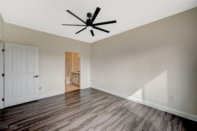 unfurnished bedroom featuring a ceiling fan, ensuite bath, wood finished floors, and baseboards