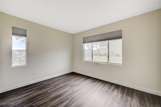 unfurnished room featuring dark wood-type flooring and baseboards